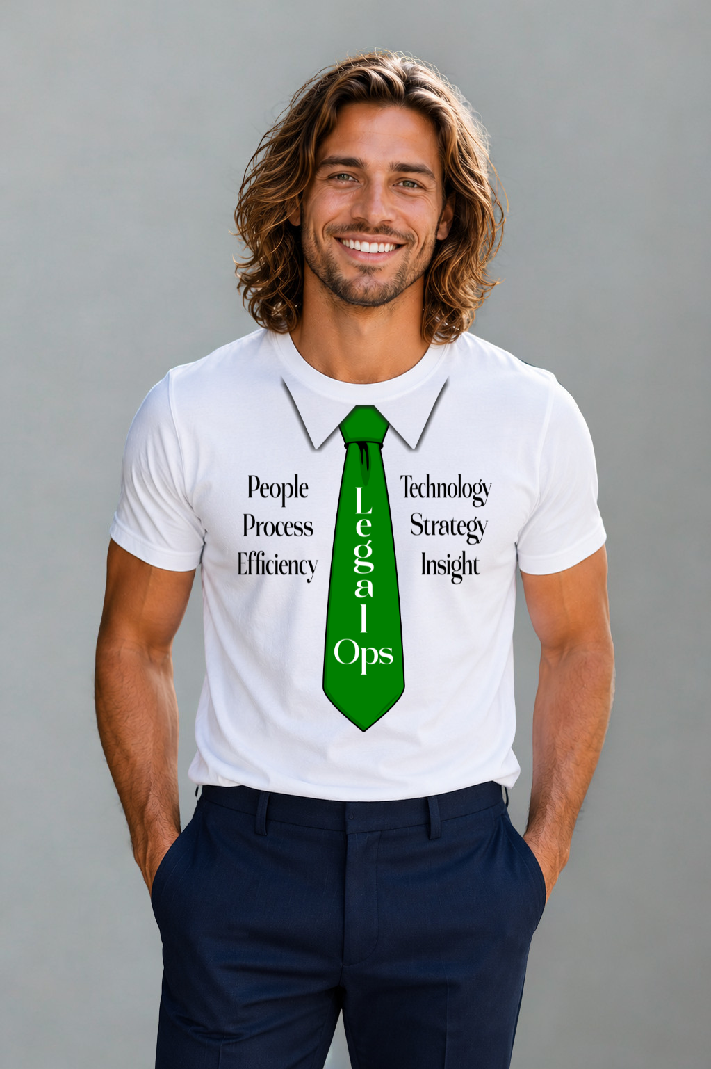 A smiling man with long brown hair stands against a plain gray background wearing a white graphic T-shirt with a green tie design and dark navy pants.