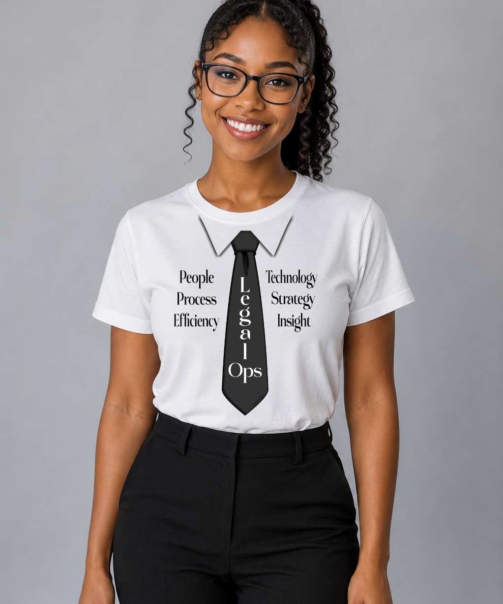 A woman wearing glasses and a white graphic t-shirt with a black tie design and the text 'Technical Ops' and 'People Process Efficiency Technology Strong Insight', paired with black pants, against a solid gray background.
